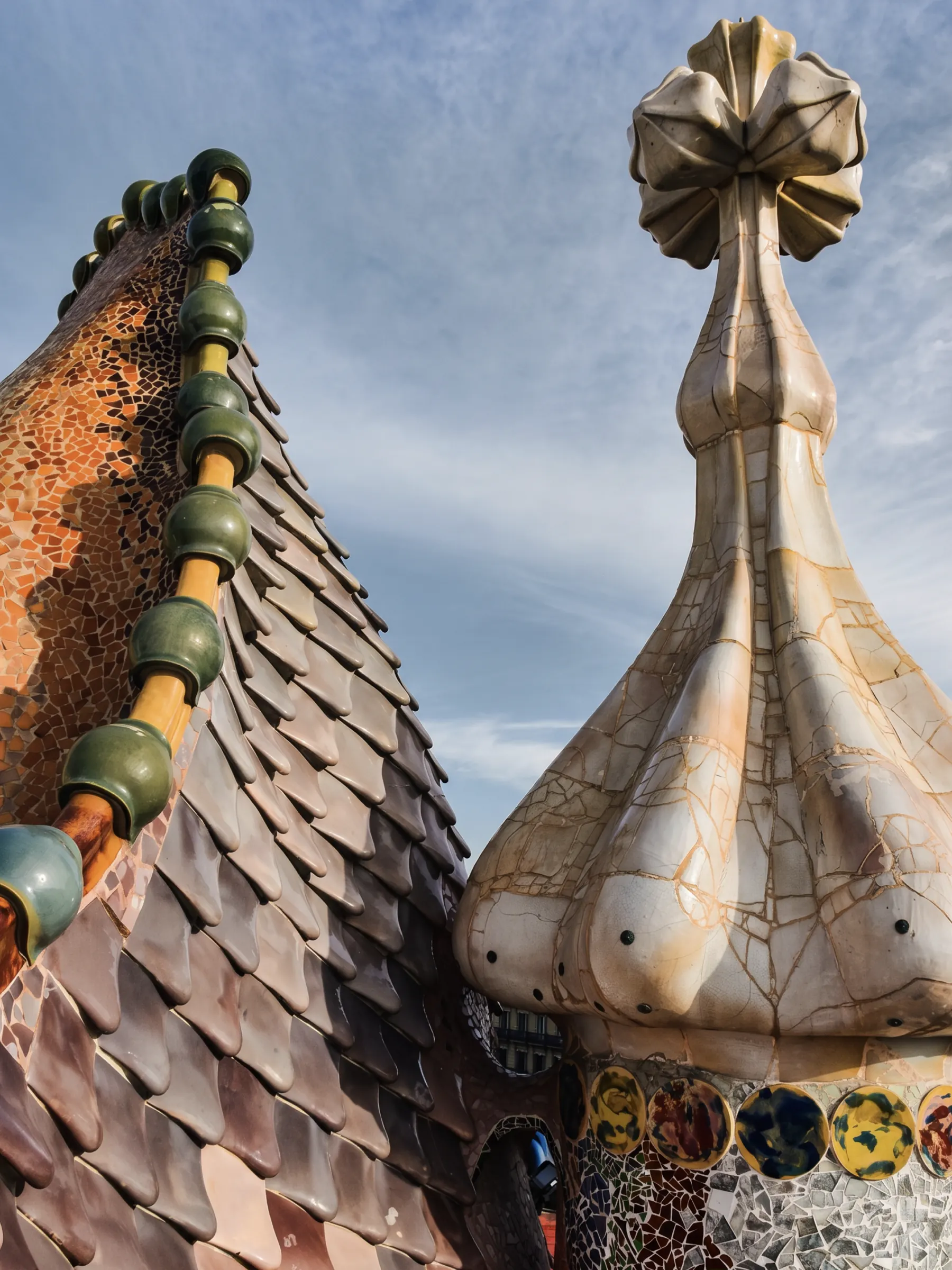 Rooftop of Casa Batlló in Barcelona: ceramic scales and a mosaic tower against the sky.