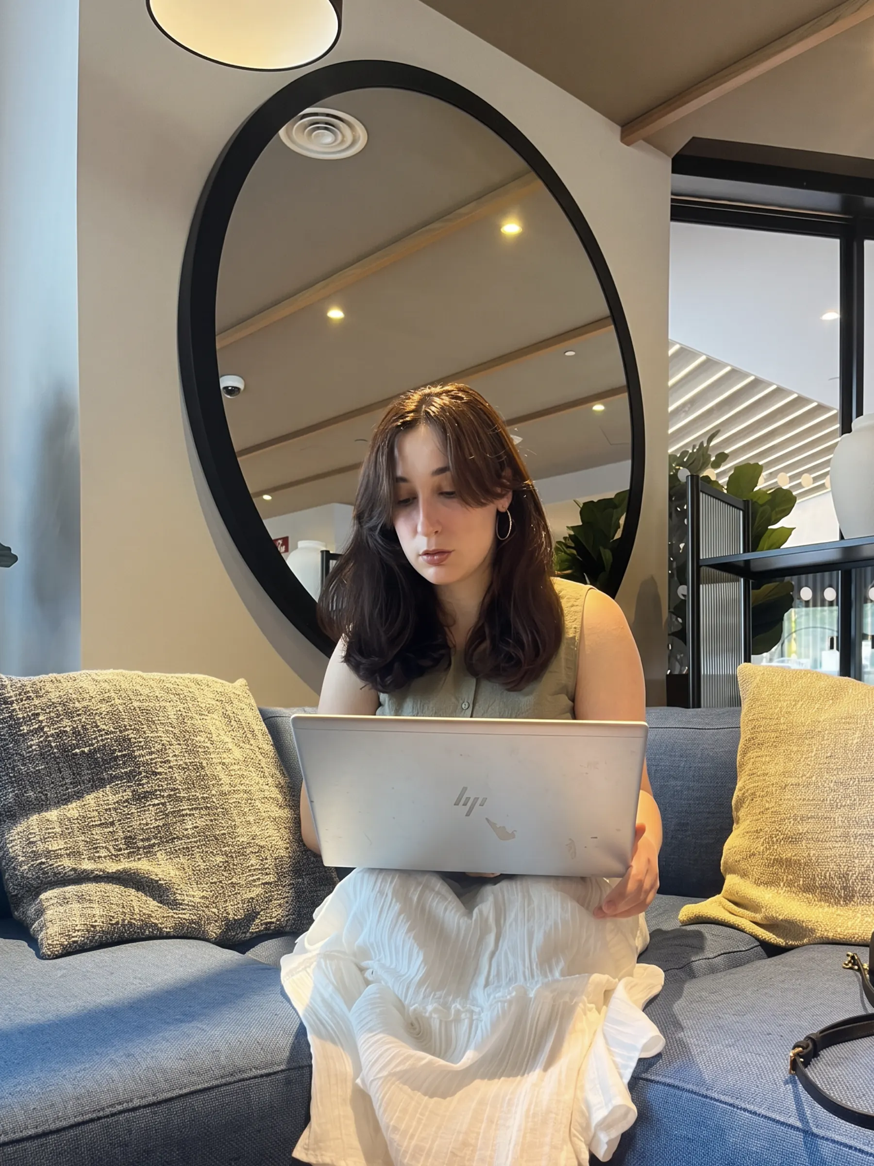 Claudia Miralles Berna working from a sofa in a bright Madrid lounge.