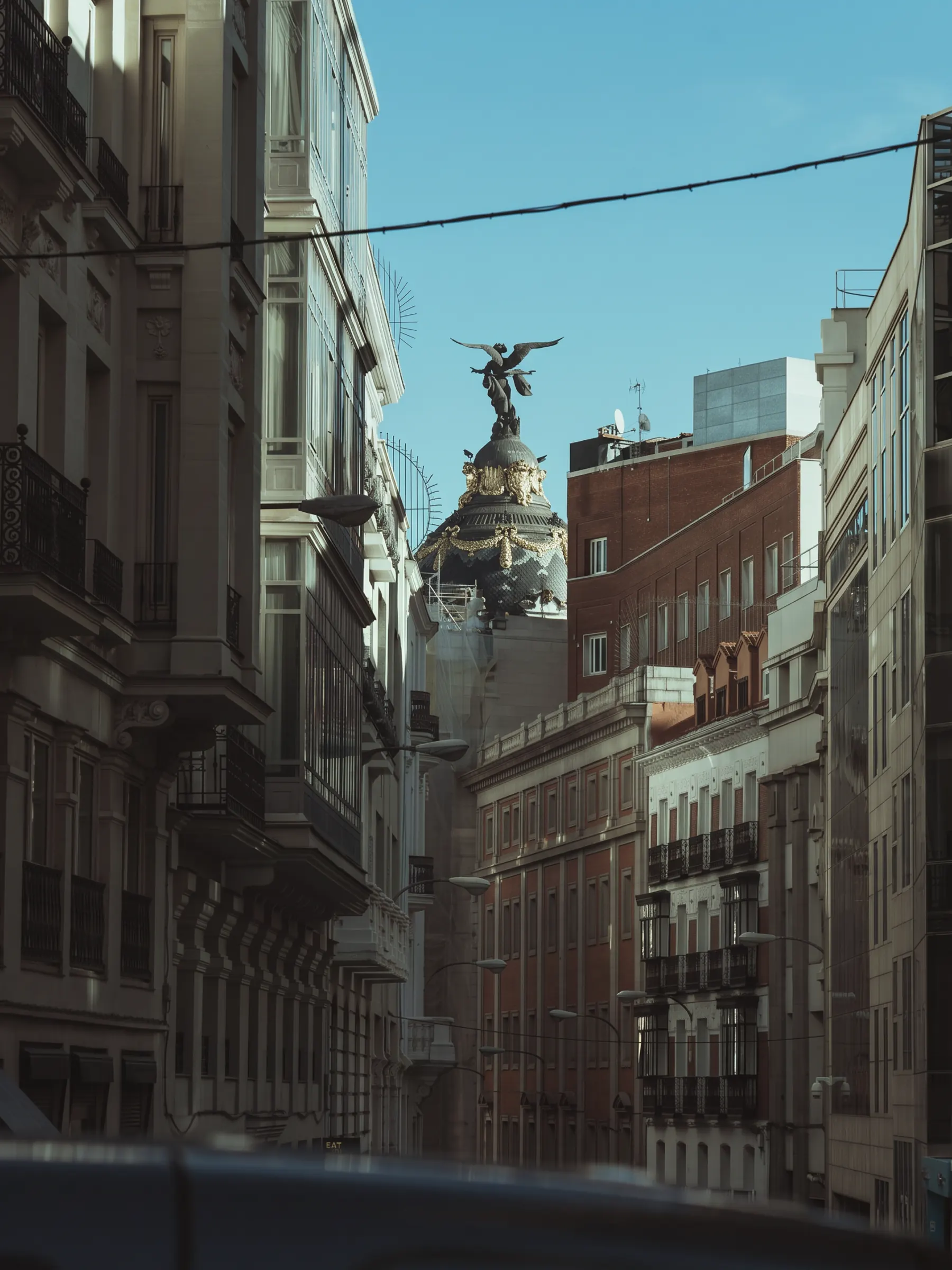 Madrid's Metropolis building rising over Calle de Alcalá, its winged figure against a clear sky.