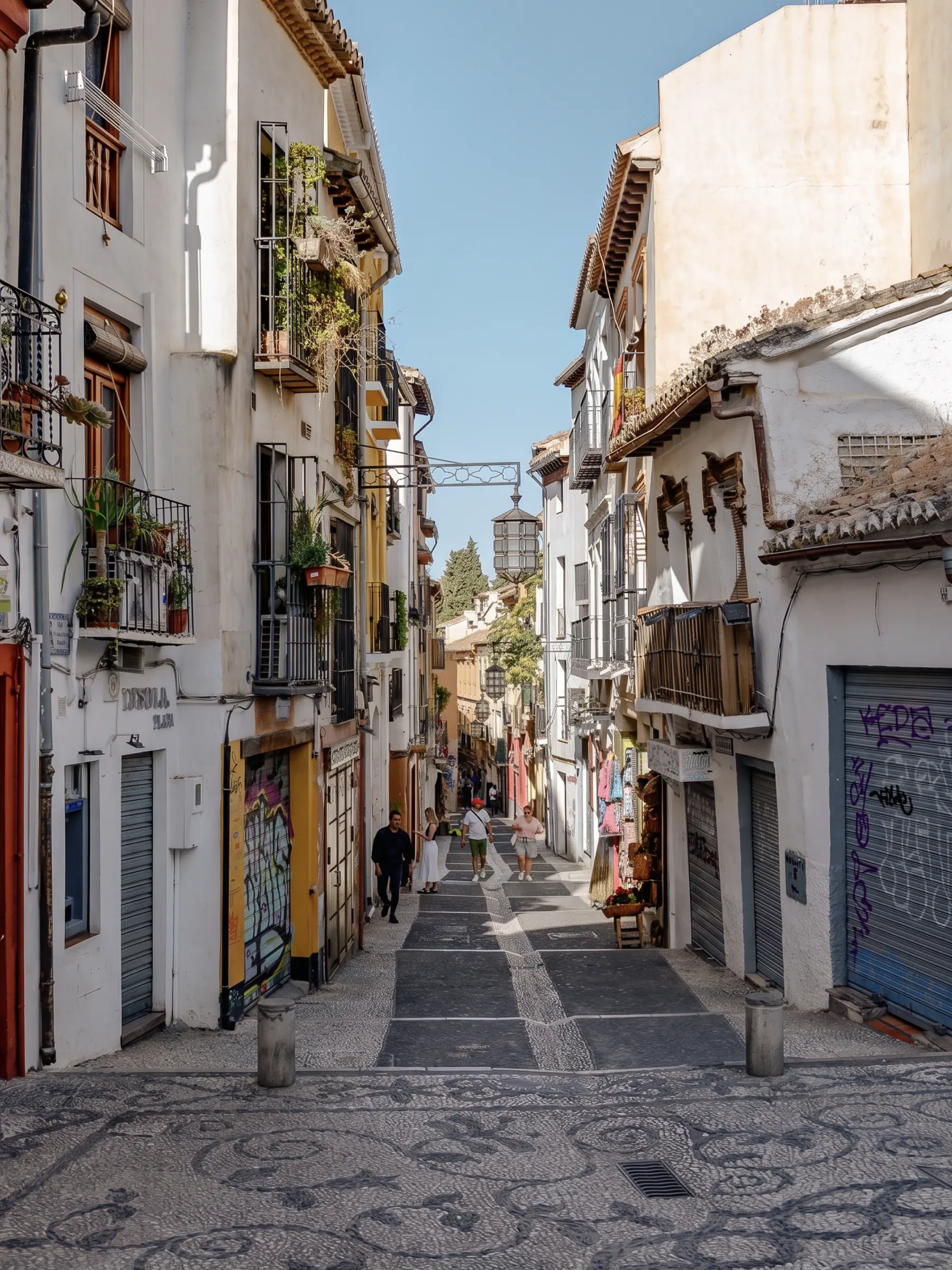 A whitewashed old-town street in Andalusia, patterned stone underfoot and balconies overhead.