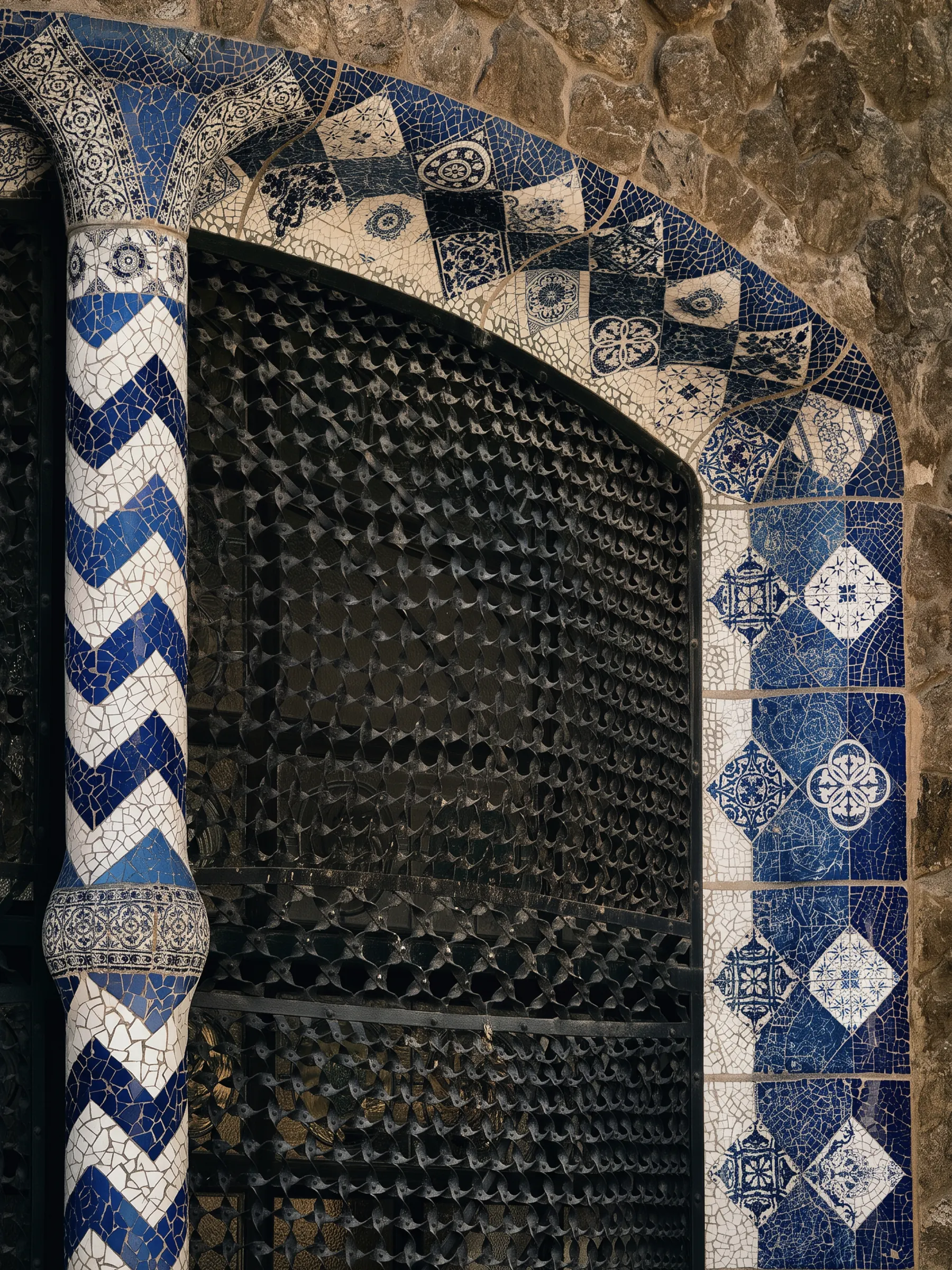 A tiled Modernista doorway in blue and white azulejo, its iron grille in shadow.